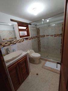 y baño con ducha, aseo y lavamanos. en Apartahotel saquenzipá en Villa de Leyva
