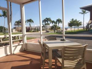 een tafel en stoelen op een veranda met uitzicht op het strand bij Ragged Edge Resort & Marina in Islamorada