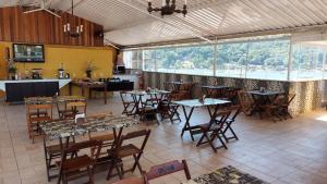 a restaurant with tables and chairs and a large window at Itacuruçá Inn in Itacuruçá