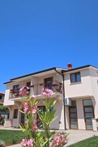 una casa blanca con flores rosas delante en Solaria Apartments Porec, en Poreč