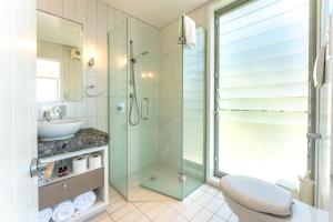 a bathroom with a shower and a toilet and a sink at The Sands - Apartment 26 - Stay Waiheke in Onetangi