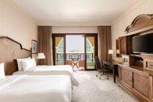 a hotel room with two beds and a flat screen tv at Shangri-La Qaryat Al Beri, Abu Dhabi in Abu Dhabi