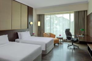 una habitación de hotel con 2 camas y una silla en Radisson Blu Plaza Hotel Mysore, en Mysore