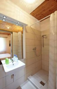 een badkamer met een wastafel en een douche met een spiegel bij Adriana Guesthouse in Jezerce
