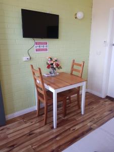 - une table à manger avec 2 chaises et une télévision murale dans l'établissement Whyalla Country Inn Motel, à Whyalla