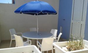 uma mesa azul e cadeiras com um guarda-sol azul em Casuzze Country em Marina di Ragusa