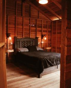 1 dormitorio con 1 cama en una habitación con paredes de madera en Cabañas Campestres El Naranjo, en San Cristóbal de Las Casas