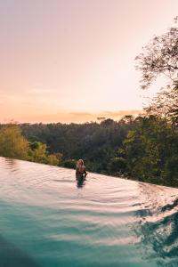 a woman swimming in a body of water at Bisma Eight - CHSE Certified in Ubud