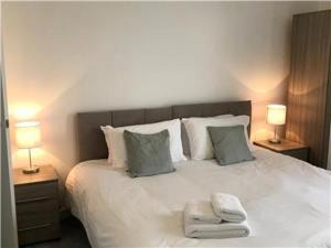 a bedroom with a large white bed with two lamps at Lower Ashby Apartments in Scunthorpe