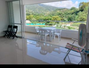ein Esszimmer mit einem Tisch und Stühlen sowie einem großen Fenster in der Unterkunft Apartamento Citadela Di Sole Santa fe De Antioquia in Santa Fe de Antioquia