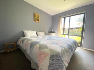 ein Schlafzimmer mit einem Bett und einem großen Fenster in der Unterkunft 4 Tarndale Place in Hanmer Springs
