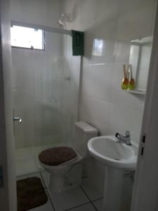 a white bathroom with a toilet and a sink at Casa com piscina em Balneário Camboriú in Balneário Camboriú