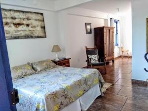 a bedroom with a bed and a chair at Tiradentes Pousada Ramalhete in Tiradentes