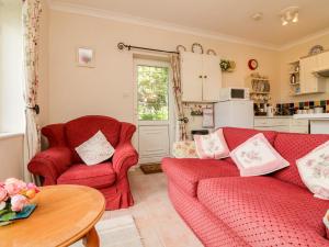 ein Wohnzimmer mit zwei roten Sofas und einem Tisch in der Unterkunft Claire's Cottage in Poughill