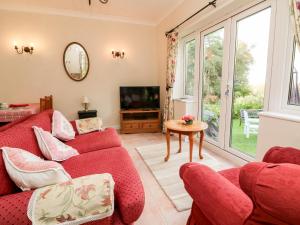 a living room with a red couch and a tv at Claire's Cottage in Poughill