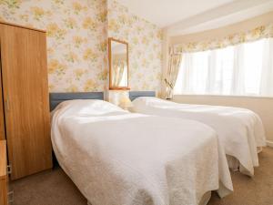 two beds in a room with floral wallpaper at Claire's Cottage in Poughill