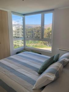 ein Schlafzimmer mit einem großen Bett und einem großen Fenster in der Unterkunft Condominio Papudo Laguna, Piscina, Laguna y Acceso Playa in Papudo