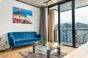 sala de estar con sofá azul y mesa de cristal en Bridgewater One Apartments, en Ciudad del Cabo