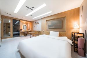une chambre avec un grand lit blanc et un bureau dans l'établissement Friendly DH Naissance Hotel by Mindrum Group, à Séoul