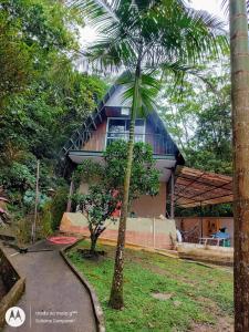 uma casa com uma palmeira em frente em CHALÉ POUSADA DO SONHO Guapimirim-RJ em Guapimirim