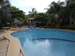 uma grande piscina num resort com palmeiras em Room in Condo - Nice condo to vacation in Playas del Coco em Coco