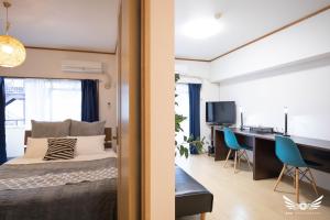 a bedroom and a living room with a bed and a desk at Gentry Hakata in Fukuoka