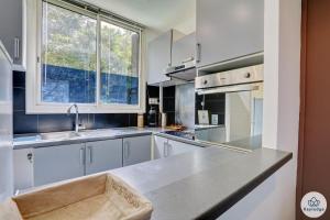 a kitchen with white cabinets and a sink and a window at T3 - Duplex Moringue 2 étoiles - Vue sur Jardin - Proche centre Saint-Denis in Saint-Denis