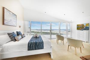 a white bedroom with a bed and a large window at The Duporth Riverside in Maroochydore