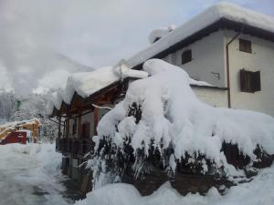 a house covered in snow next to a building at casa vacanze in Cogolo