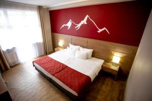エストサドクにあるAys Design Hotel Rosa Khutorの赤い壁のベッドが備わるホテルルームです。