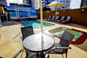 a table with chairs and an umbrella next to a pool at Sails Apartments in Forster