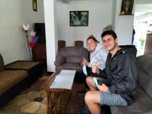 dos hombres sentados en una sala de estar dando pulgares hacia arriba en Ayos Hill Adam's Peak Free Shuttle, en Nallathanniya