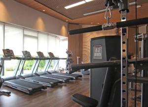 un gimnasio con una fila de barras de correr en una habitación en NOCHE - 2 bedroom Skyhouse Apartment BSD, en Tangerang