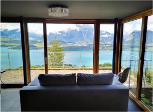 a living room with a couch in front of a large window at Chalet with view of the mountains and the Thun lake in Sigriswil
