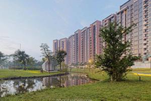 Marigold Apartment Nava Park Central BSD في تانغيرانغ: عماره فيها شجره بجانب سفح ماء