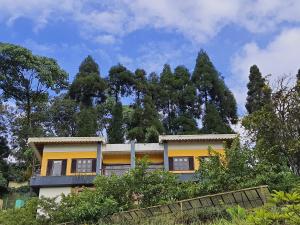 una casa amarilla con árboles en el fondo en Chamong Chiabari Mountain Retreat en Darjeeling