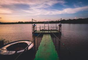 un muelle sobre un cuerpo de agua con un barco en Starling River Resort Dandeli, en Dandeli