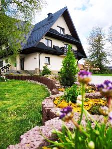 una casa con techo negro y un patio con flores en Lawenda, en Białka Tatrzanska