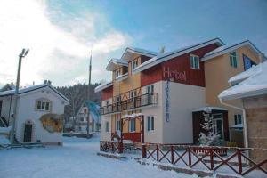 a hotel in the snow with snow covered buildings at Edelweiss Hotel in Abzakovo