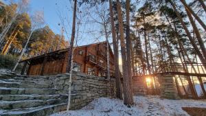 a log cabin in the woods with snow on the ground at Chalet Turgoyak Guest House in Turgoyak