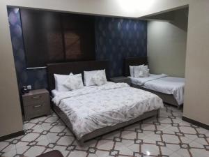 a bedroom with two beds with white comforters at Karachi Guest House in Karachi