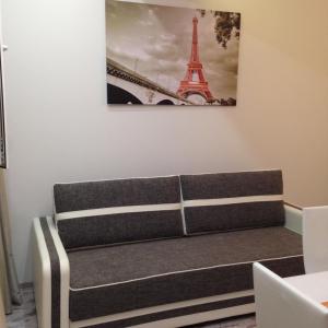 um sofá num quarto com uma fotografia da Torre Eiffel em Sea Rapsody Apartment em Adler