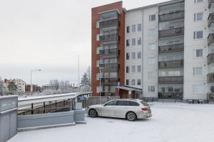 een witte auto geparkeerd op een parkeerplaats naast gebouwen bij Arctic Aurora City Suite in Rovaniemi