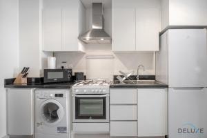 a kitchen with white cabinets and a washer and dryer at Immaculate Studio at DAMAC Celestia by Deluxe Holiday Homes in Dubai