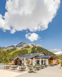 eine Lodge mit Tischen, Stühlen und Bergen im Hintergrund in der Unterkunft Berglodge Ristis in Engelberg