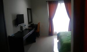 a bedroom with a bed and a desk and a television at Bumi Gumati Resort & Convention in Bogor