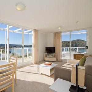 un soggiorno con divano, TV e finestre di Mantra Ettalong Beach a Ettalong Beach