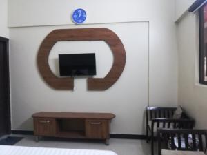 a room with a tv and a table and a clock at Karachi Guest House in Karachi