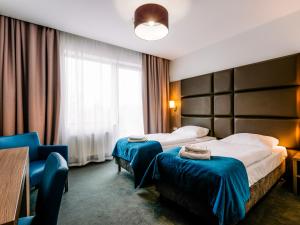 a hotel room with two beds and a chair at Hotel Delicjusz in Trzebaw