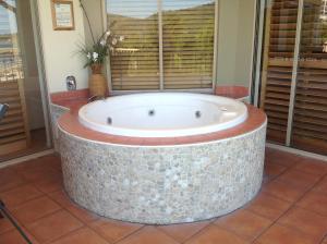 a bath tub in a room with a window at at Boathaven Bay Holiday Apartments in Airlie Beach